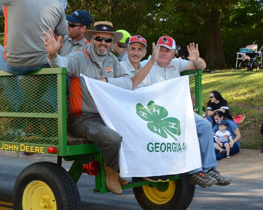 People waving from a parade float holding a 4-H banner